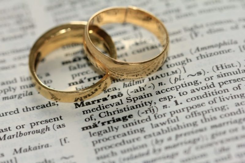 wedding rings on top of a dictionary definition of marriage