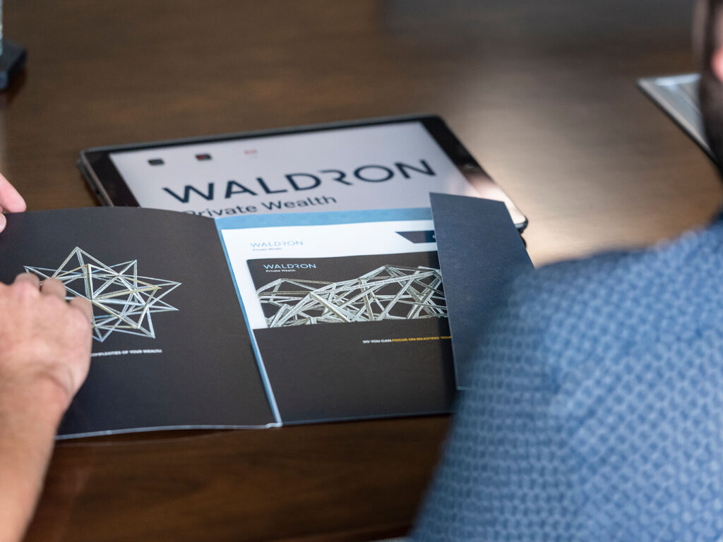 people reviewing Waldron printed materials and iPad